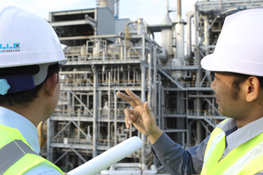 two engineer  discussing a new project with large oil refinery background